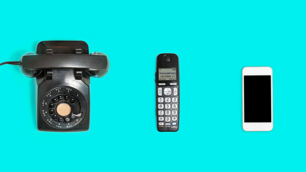 A rotary phone, landline phone, and smartphone showing the evolution of technology